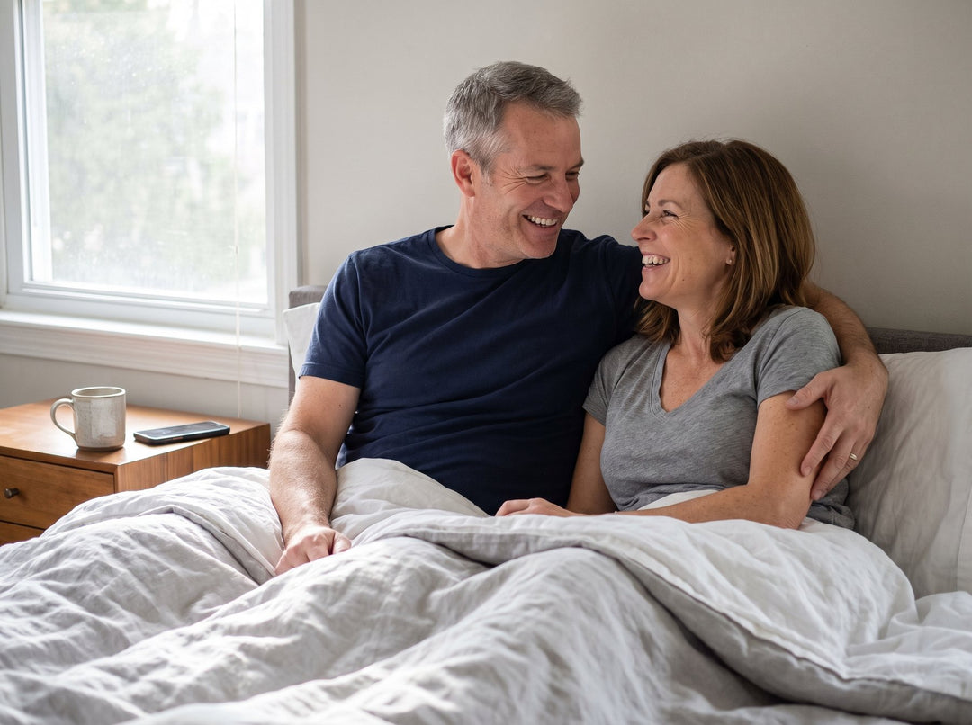 A man and his wife laughing together in bed on a weekend morning